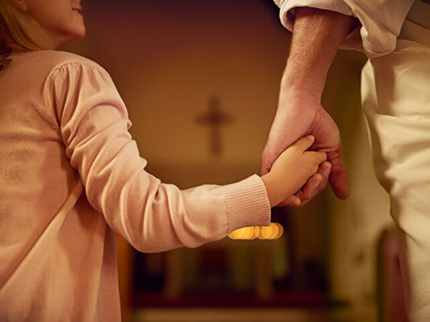 Cropped shot of a little girl holding hands with Jesus while standing inside a church