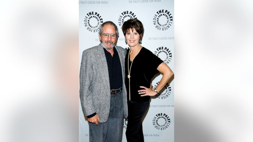 Desi Arnaz Jr. and Lucie Arnaz leaning in close to each other and smiling in casual wear.