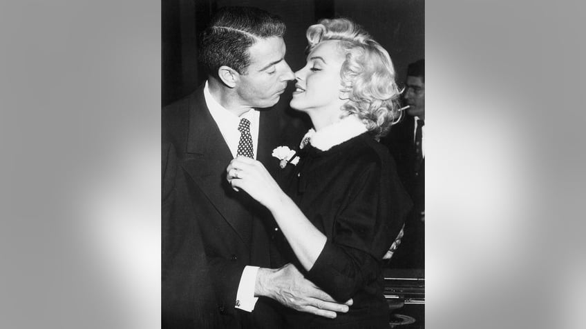 Marilyn Monroe and Joe DiMaggio leaning in for a kiss.