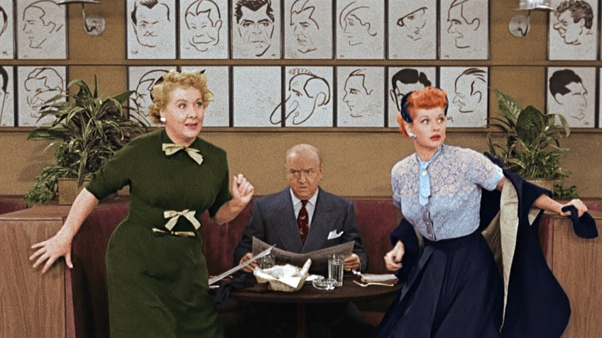 William Frawley sitting at a table in between a shock Vivian Vance and Lucille Ball