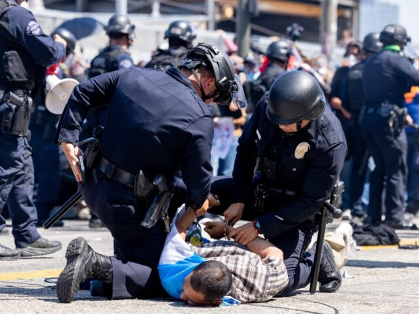 LAPD officers arrest a protester wearing stilts during an anti-ICE protest in downtown Los