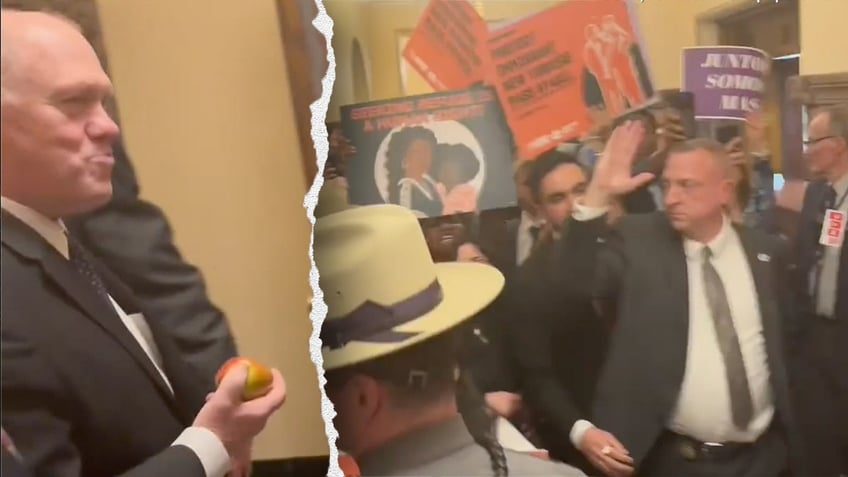 Tom Homan eats an apple in front of protesters on Wednesday.