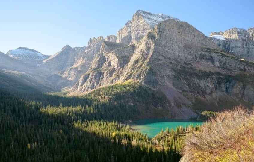 The turquoise water of Grinnell Lake is bathed in sunlight in Glacier National Park, Monta