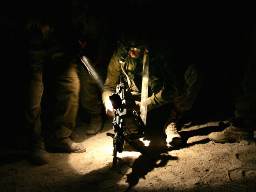 An Israeli soldier checks his weapon along the Israeli-Lebanese borders as he and his comr