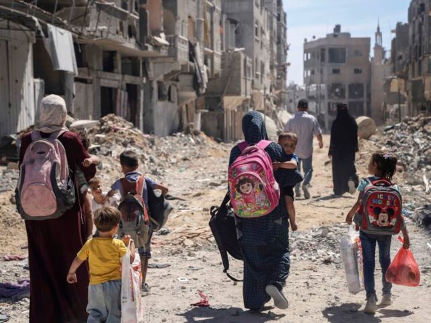 FILE - Palestinian women and their children walk though destruction in the wake of an Isra