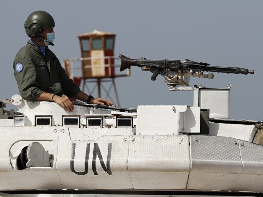 An Italian U.N. peacekeeping soldier sits on a tank at a road that links to a UNIFIL base