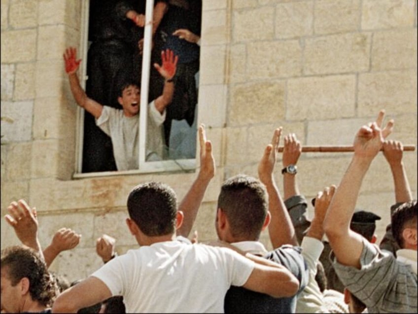 A Palestinian youth proudly shows Israeli blood on his hands as he is cheered by fellow pr