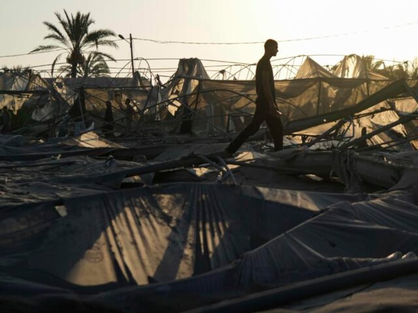 Palestinians look at the destruction after an Israeli airstrike on a crowded tent camp hou