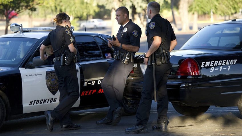 Stockton Police stand outside a pair of parked cruisers