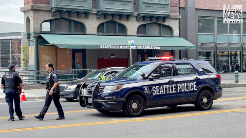 Seattle police SUV on street with police officers in front of it