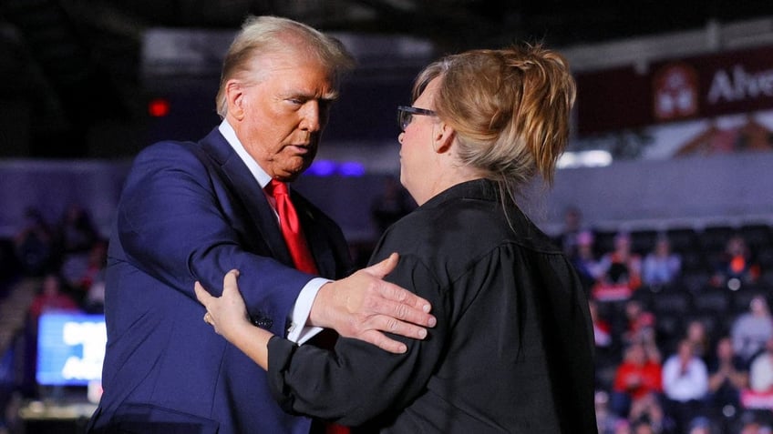 Donald Trump and Patty Morin embrace on a stage during a Trump rally in Reading, Pennsylvania