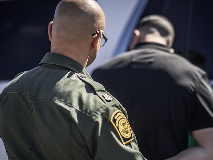 Border Patrol agent arrests a migrant and puts him in handcuffs after he illegally crossed