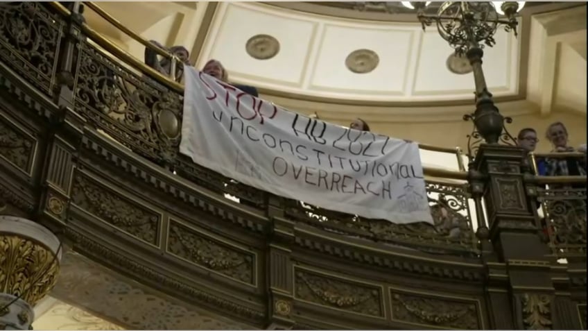 Illinois state capitol protest sign hangs from balcony