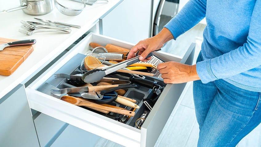 woman organizing a drawer with kitchen utensils