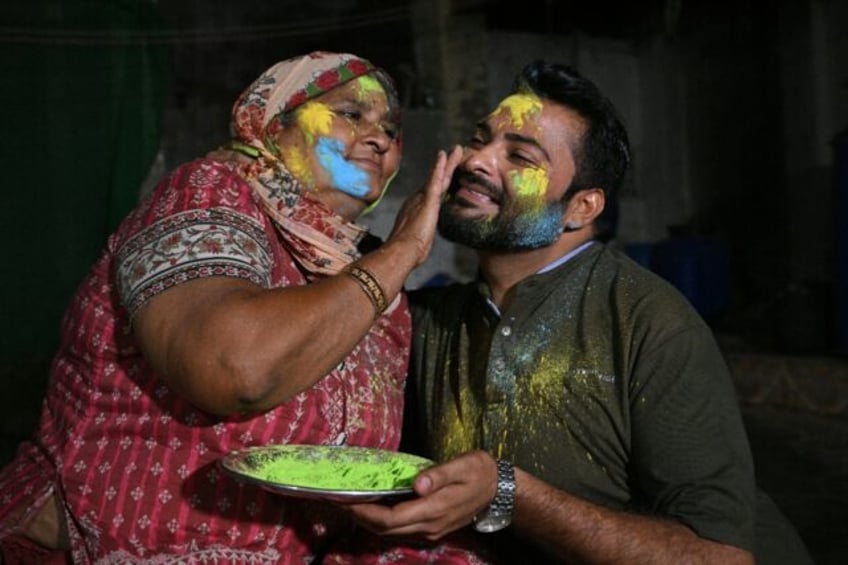 A woman paints the face of her son as they celebrate the Hindu festival of Holi in the des