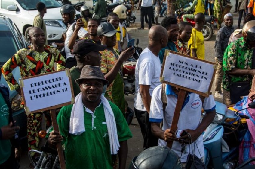 Demonstrators hold up placards during a march against the high cost of living in Cotonou,