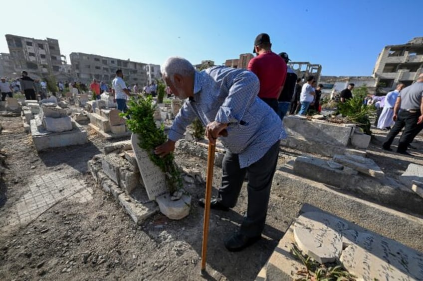 Syrians visit the graves of their loved ones in the Jobar suburb of Damascus on the first