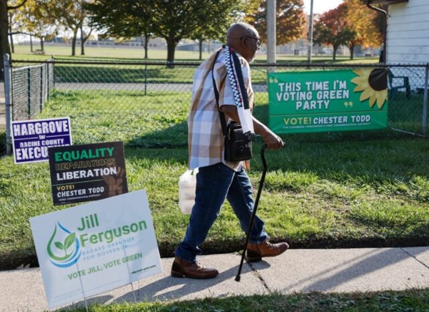 Chester Todd walks past campaign signs outside his home in Racine, Wisconsin, where he's r