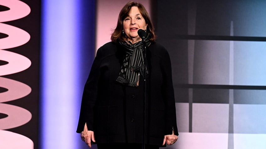 Ina Garten speaks on stage at the Webby Awards wearing a black outfit and patterned black scarf