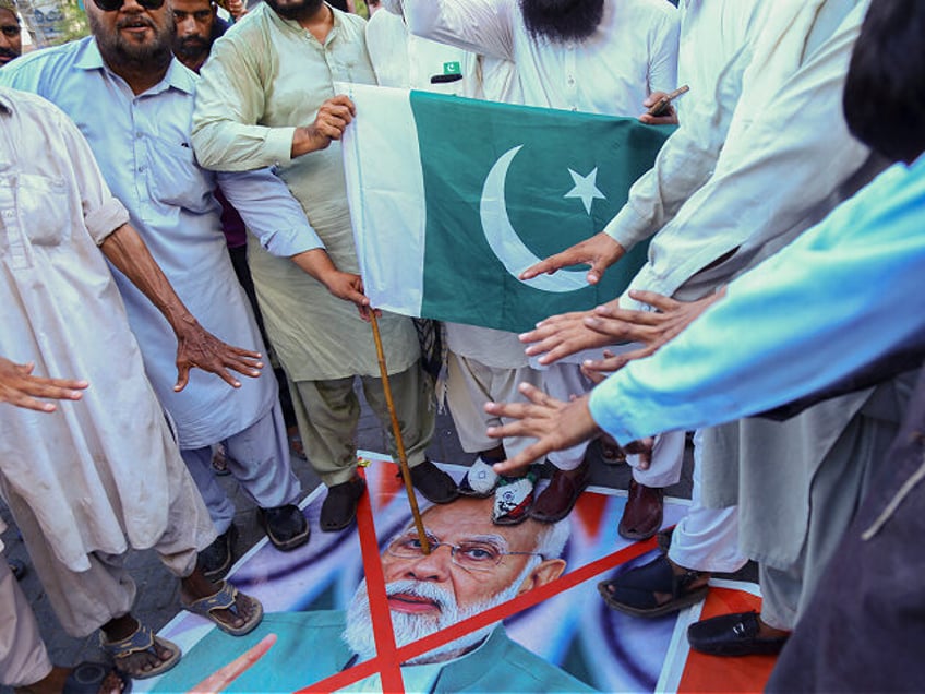 Supporters of Pakistan Sunni Tehreek stand on a photo of Indian Prime Minister Narendra Mo