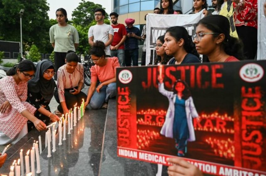 Medical professionals light candles as they pay tribute to a doctor who was raped and mur