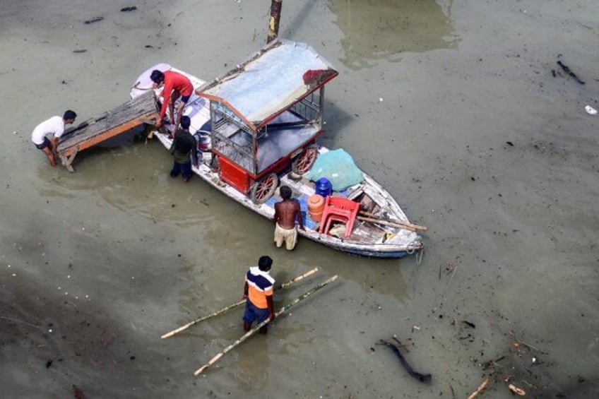 Flood-affected residents move their belongings on a boat following heavy monsoon rains in