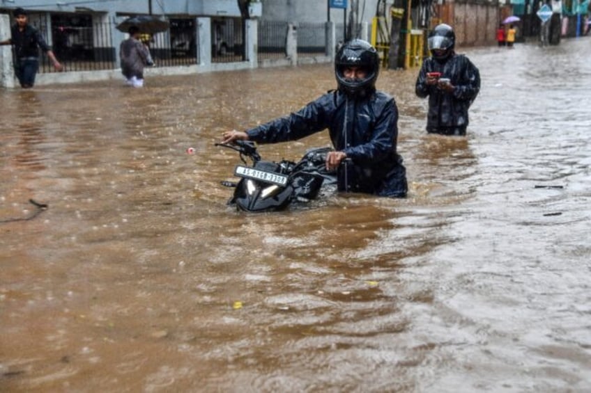 Residents wade through a flooded street after heavy rainfall in Guwahati, in India's state