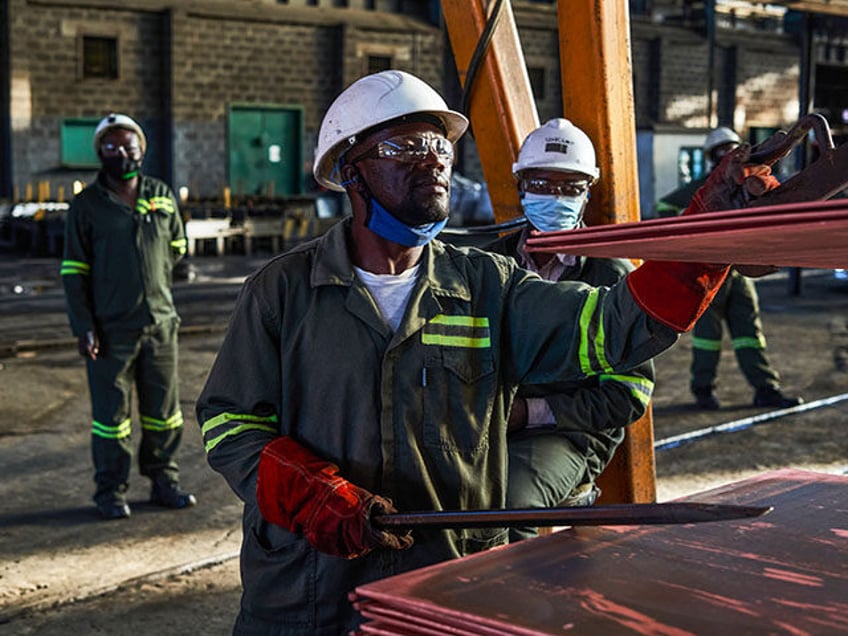 A worker inspects stacks of copper plates ready for shipping at the Mufulira refinery, ope