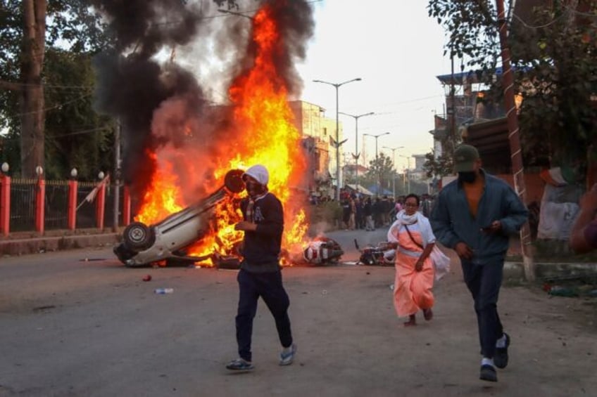 People run past burning vehicles during a protest in November to condemn the alleged killi