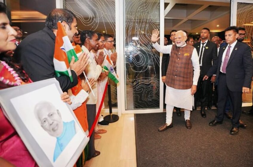 Indian Prime Minister Narendra Modi greets people holding Indian flags as he arrives in Gu