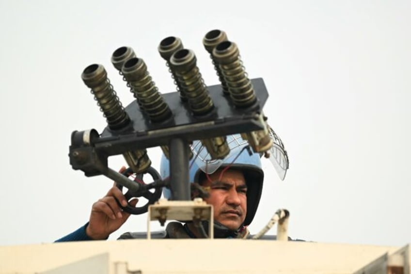 An Indian security officer stands atop an armoured vehicle at a roadblock during protests