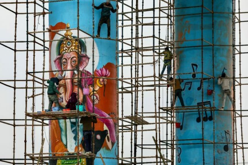 Workers paint a mural of Hindu deity Ganesha ahead of the Kumbh Mela, which organisers exp