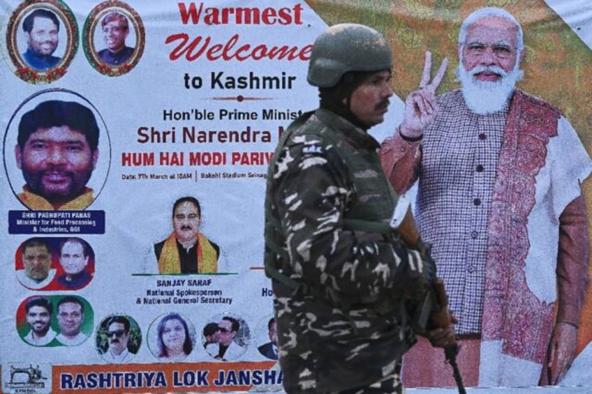 An Indian security officer stands guard in front of a poster with a portrait of Indian Pri