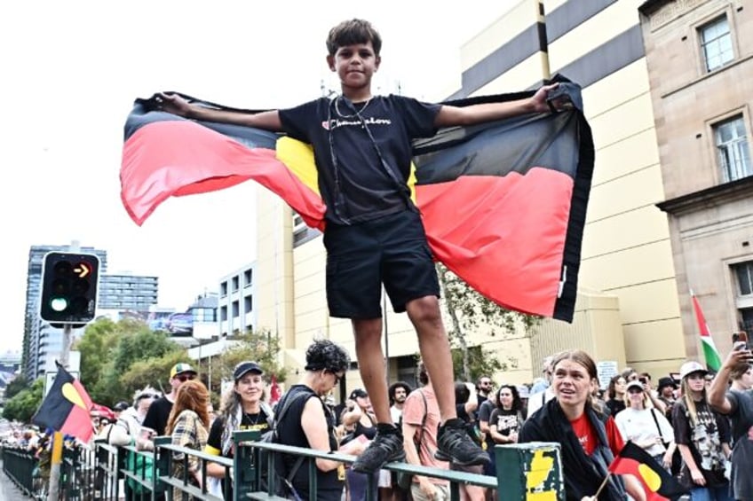 A boy with an Aboriginal flag joins annual "Invasion Day" protests in Sydney