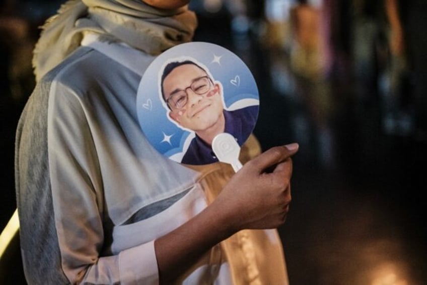 Supporters of Indonesian presidential candidate Anies Baswedan display posters, paper fans