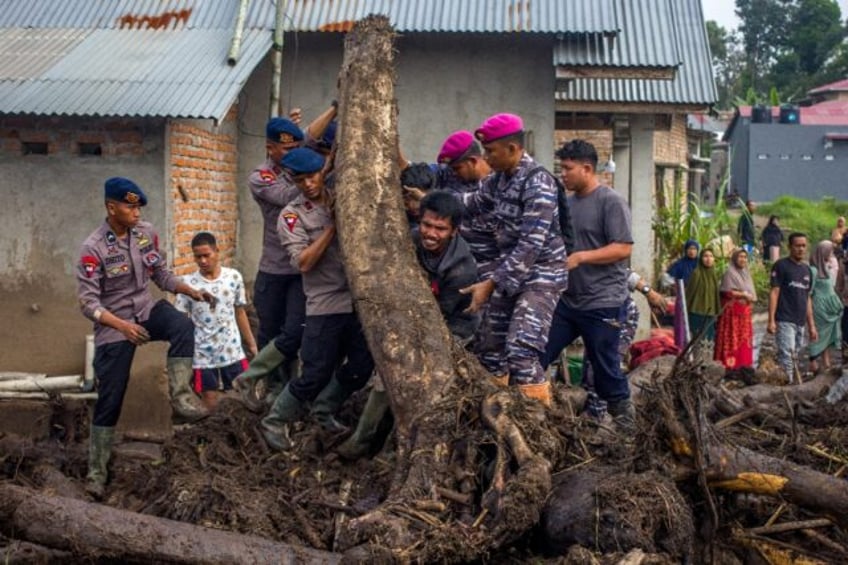 Rescue teams and people move logs that had washed into residential areas in western Indone