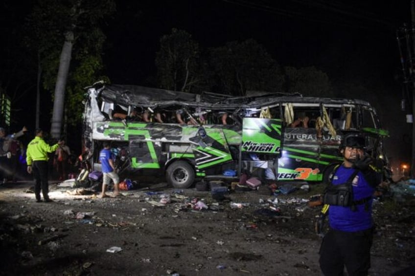 Officers check the debris and belongings of passengers after a bus crash on Java island