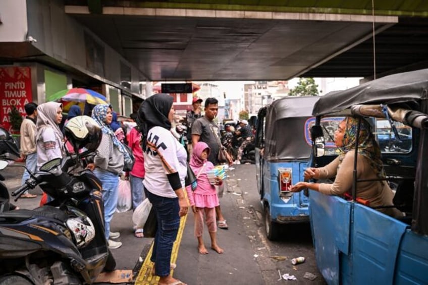 Indonesian single mother Ekawati (R) looks for autorickshaw fares in Jakarta