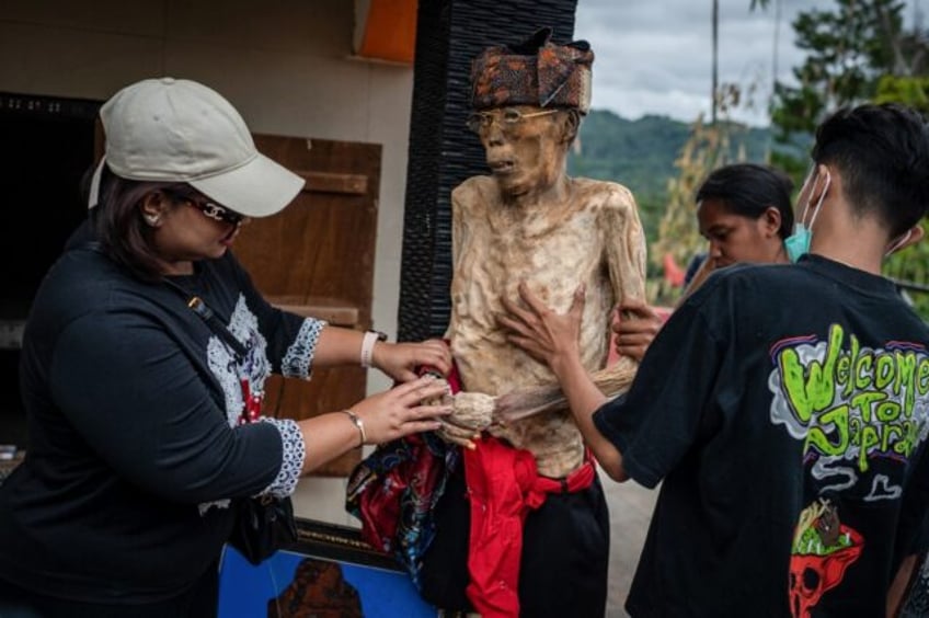 Family members of the Toraja ethnic group dress the exhumed body of their relative