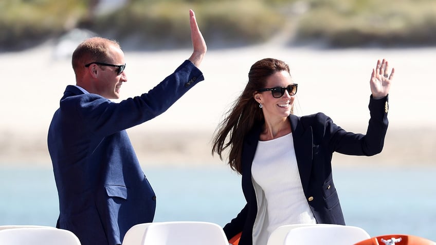 Prince William and Kate Middleton waving near a beach.
