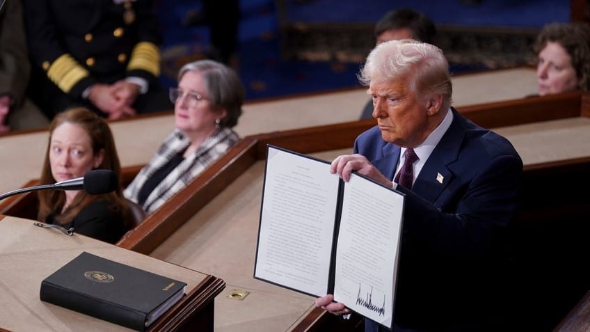 Donald Trump holds a signed executive order