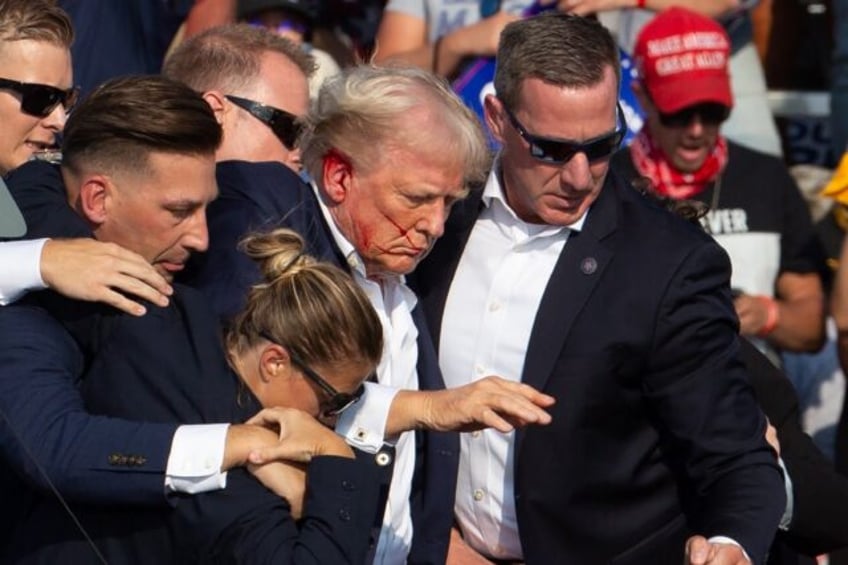 Secret Service agents shield former president Donald Trump as he is escorted off the stage