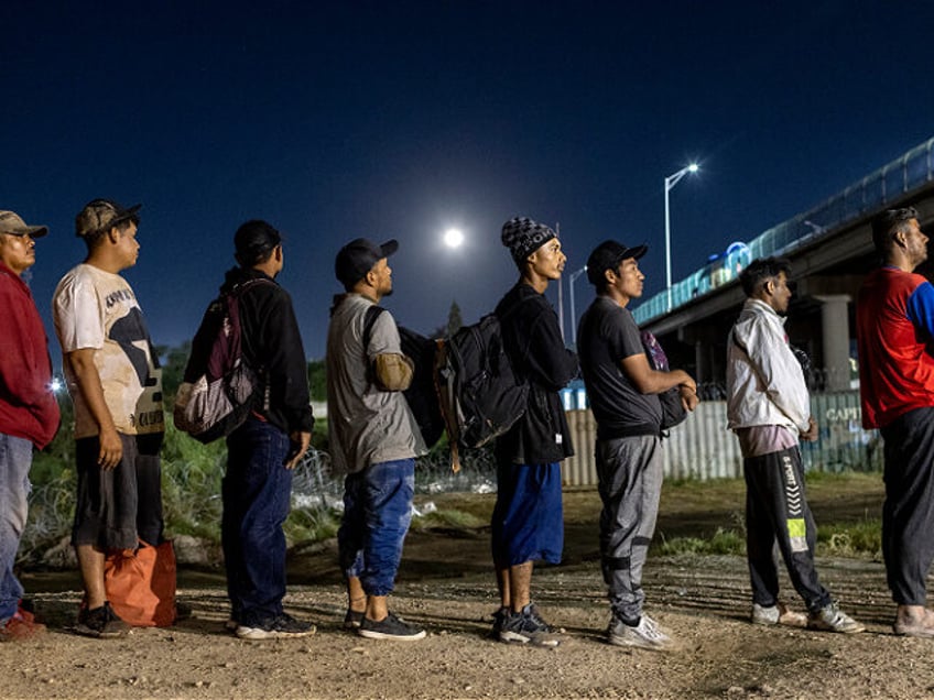 EAGLE PASS, TEXAS - SEPTEMBER 29: Under a full moon Venezuelan immigrants stand in line to
