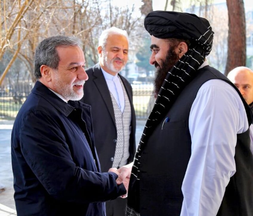 Iranian Foreign Minister Abbas Araghchi (L) shakes hands with his Afghan counterpart Amir