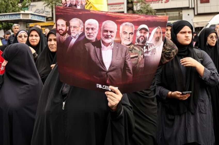 An Iranian woman holds a poster displaying slain militant leaders including Hamas's Ismail