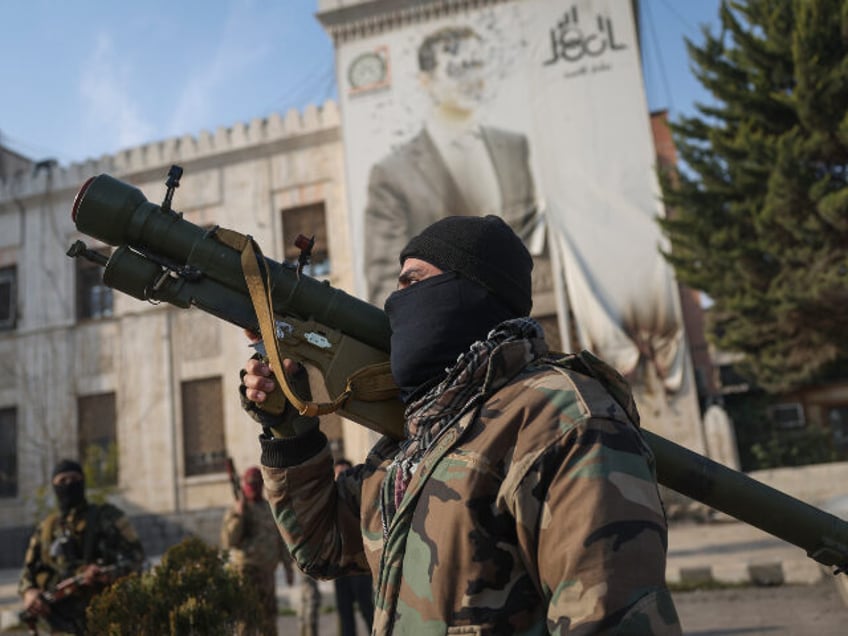 A Syrian opposition fighter holds a rocket launcher in front of the provincial government