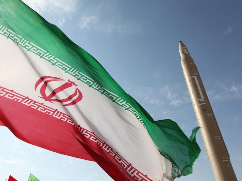 A picture taken on August 20, 2010 shows an Iranian flag fluttering at an undisclosed location in the Islamic republic next to a surface-to-surface Qiam-1 (Rising) missile which was test fired a day before Iran was due to launch its Russian-built first nuclear power plant. Iranian Defence Minister Ahmad Vahidi …