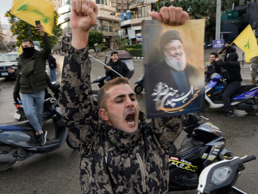 A man celebrates carrying a picture of slain Hezbollah leader Hassan Nasrallah in Dahiyeh,