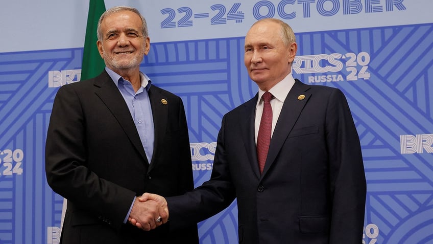 Russian President Vladimir Putin shakes hands with Iranian President Masoud Pezeshkian during a meeting on the sidelines of the BRICS summit in Kazan, Russia