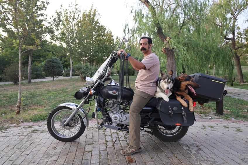 An Iranian arrives with his dogs on the back of his motorcycle in a park in Tehran on June 8, 2025. Iranian authorities have expanded a ban on walking dogs in public to multiple cities nationwide, citing public health, social order and safety concerns, domestic media reported on June 8. Owning and walking dogs has been a contentious topic since the 1979 Islamic revolution in Iran, though there is no law outrightly banning dog ownership. (Photo by ATTA KENARE / AFP) (Photo by ATTA KENARE/AFP via Getty Images)